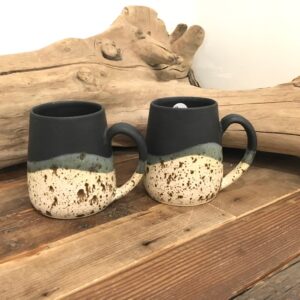 two Pottery Mugs - Black Matte top with speckled bottoms on wood table