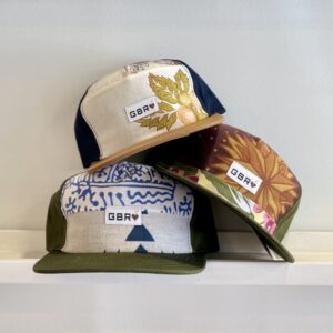 accessories & apparel| three scrap hats in a pile on shelf| handmade ball caps | recycled material | green bean reloved canada | unique hats saskatoon